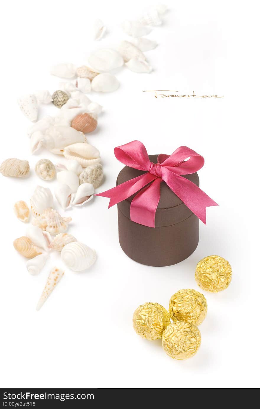 Holiday gift with red riband and various seashells on the white background.