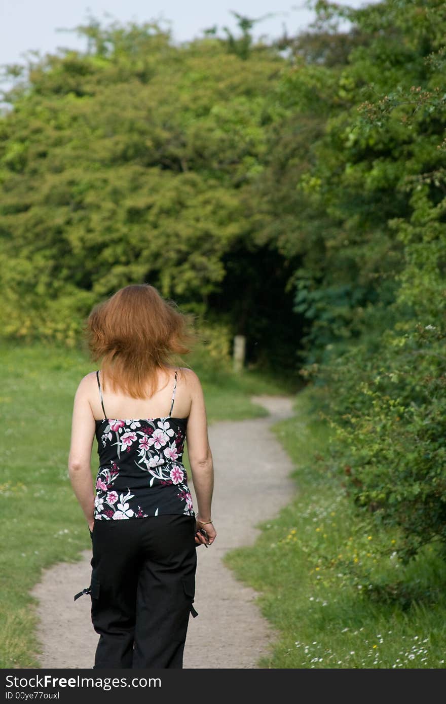 A woman walking with red hair in a field.