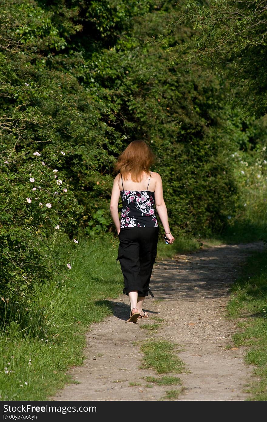 A woman walking with red hair in a field.