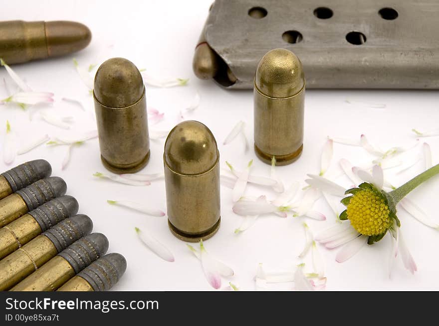 Golden bullets on flower bucks, ammunition magazine in background, ripped flower. Golden bullets on flower bucks, ammunition magazine in background, ripped flower