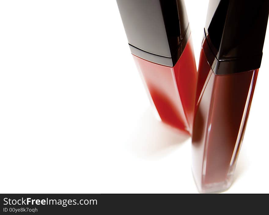 Two shiny red lipglosses on white background. selective focus. room for text right on the pictures. clipping path