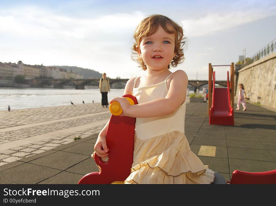 A playful little girl is rocking on the playground. A playful little girl is rocking on the playground.