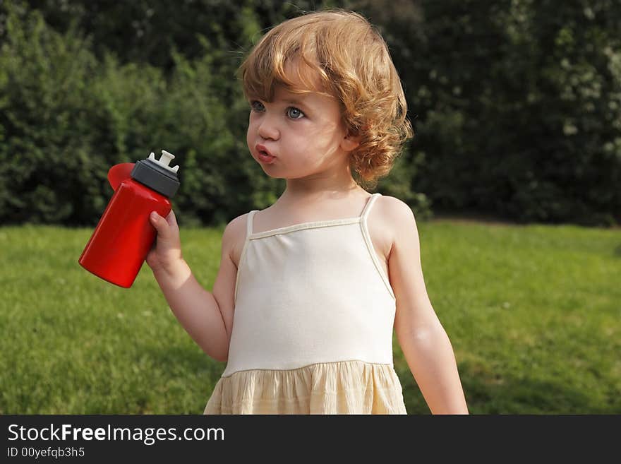 A little girl with a red flask in her hand.