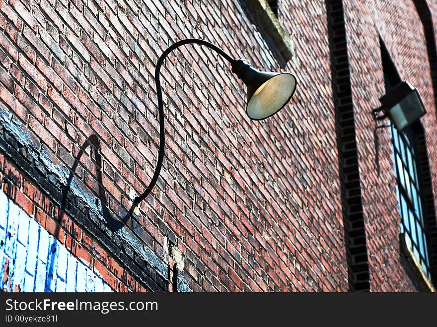 Grunge brick wall with curved lamp fixture turned on. Grunge brick wall with curved lamp fixture turned on