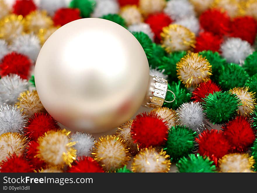 Silver Christmas bauble resting on colorful puff ball decorations. Silver Christmas bauble resting on colorful puff ball decorations