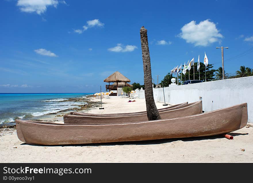 Canoes under the broken palm on San Miguel town beach (Cozumel island, Mexico).