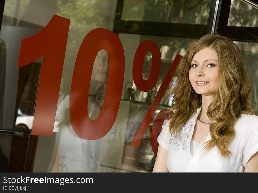 Pretty woman standing near shop window with 10% discount sign. Pretty woman standing near shop window with 10% discount sign