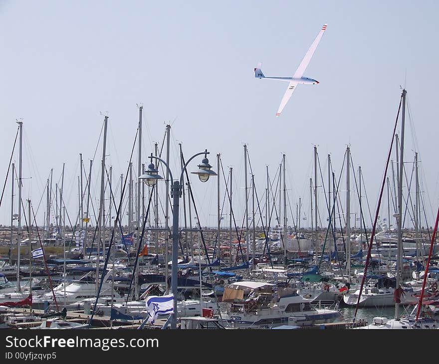 Marina view with yachts, motorboats and plane in the sky. Marina view with yachts, motorboats and plane in the sky