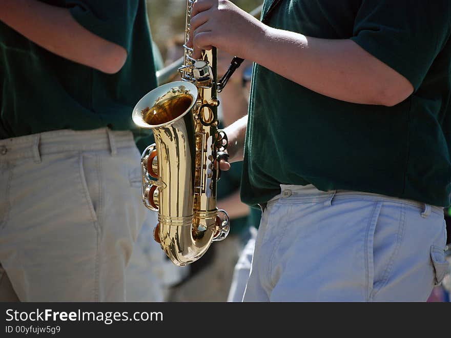 Band member playing the saxaphone in a parade. Band member playing the saxaphone in a parade.