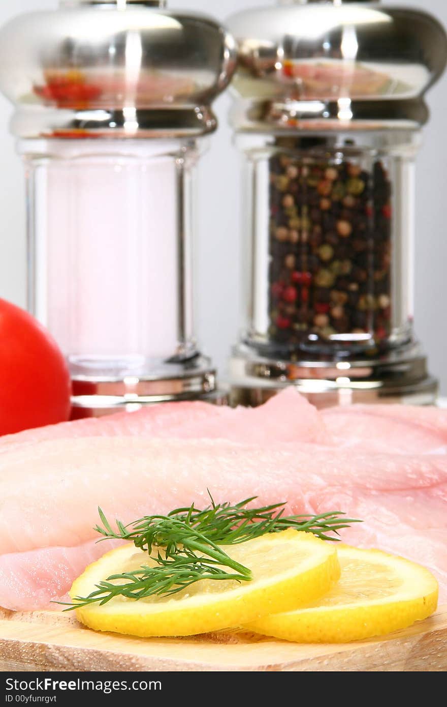 Fresh Ttilapia with tomato, lemon, dill on cutting board.  St. Peter's fish.