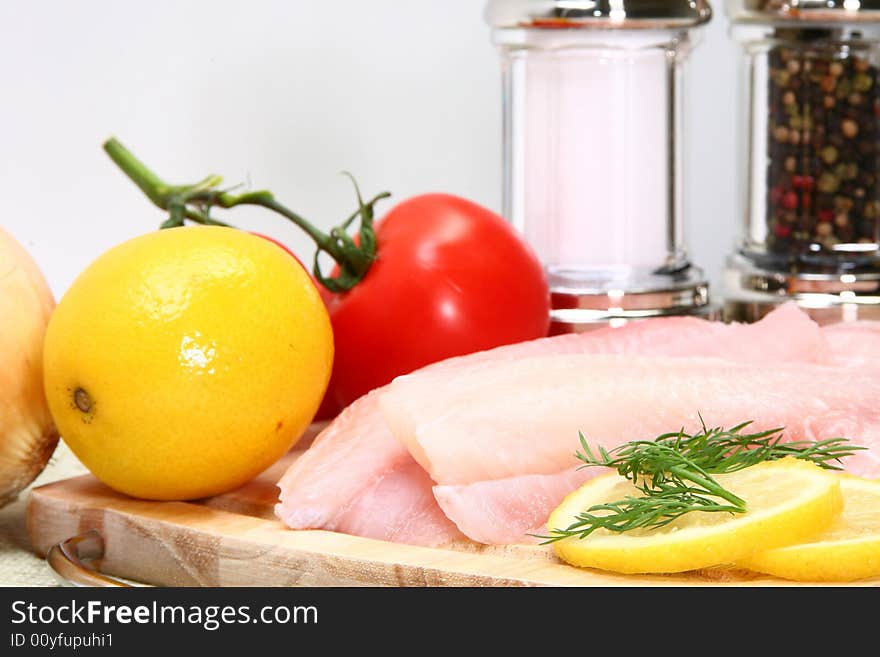 Fresh Ttilapia with tomato, lemon, dill on cutting board.  St. Peter's fish.