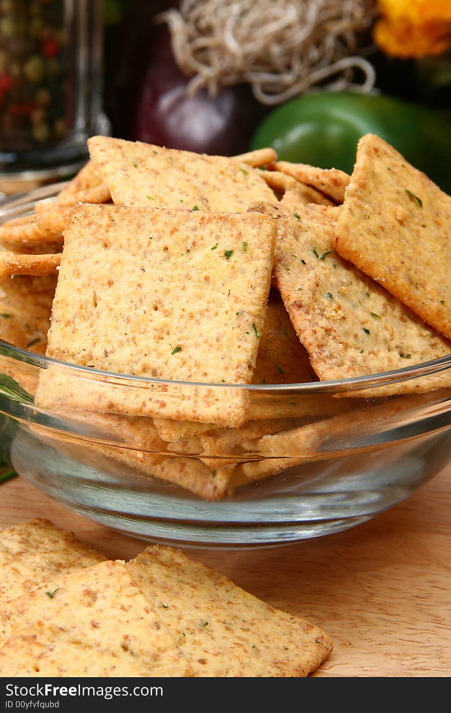 Square sour cream and chive flavored crackers in glass bowl on cutting board in kitchen or resturant.