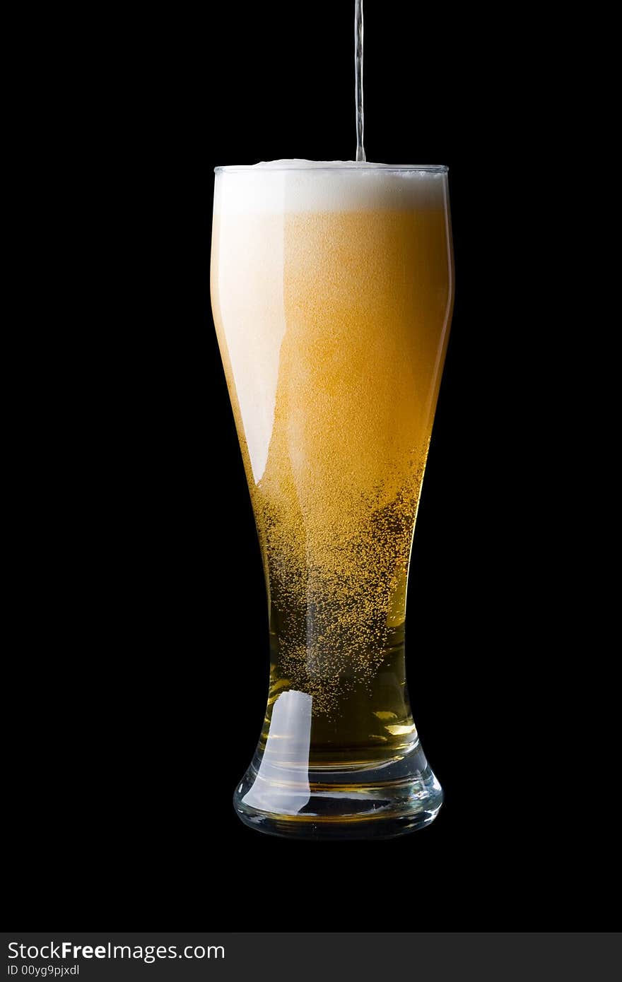 Fresh foamy beer in a glass on a black background.