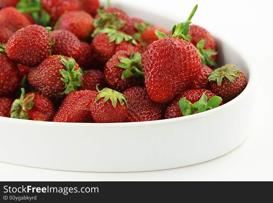 Some fresh strawberries in white bowl; white background