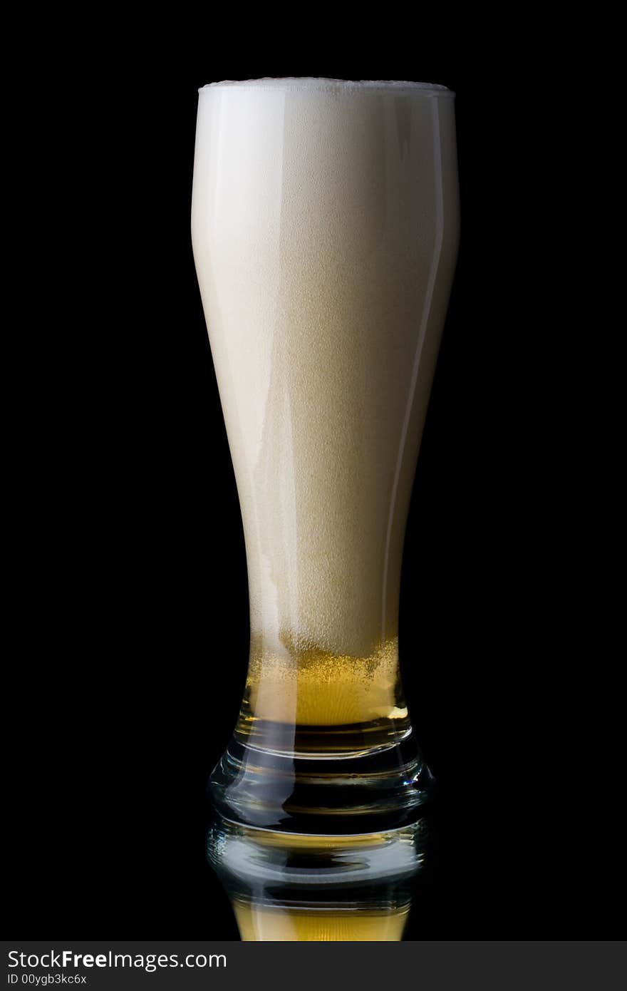 Fresh foamy beer in a glass on a black background.