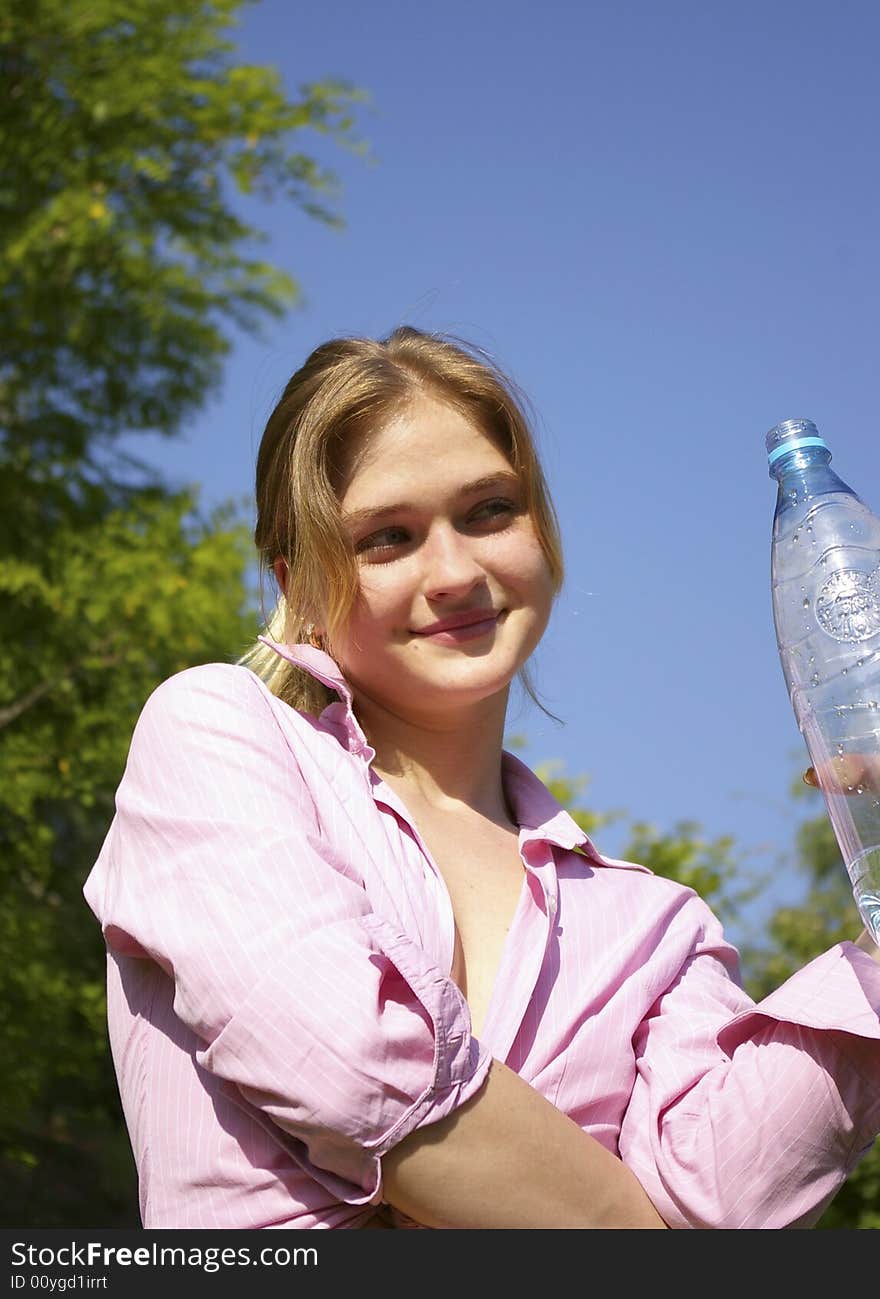 The beautiful woman drinks water from a bottle