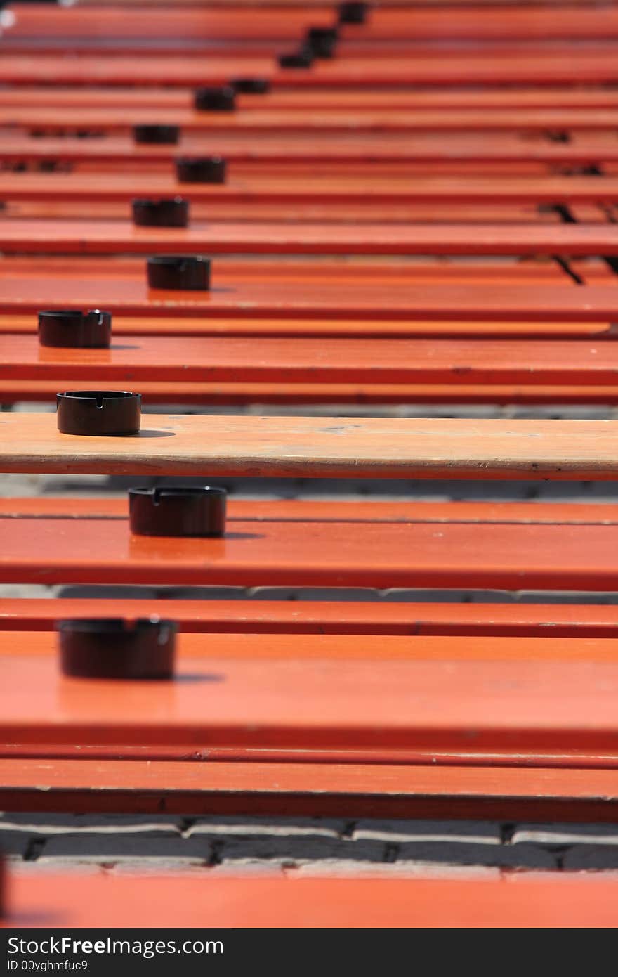 Black ashtrays on orange ale benches