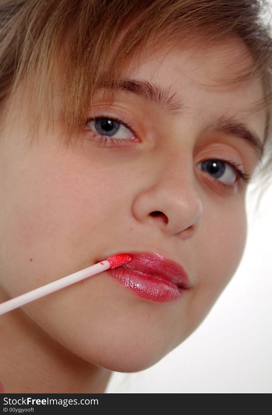 Beauty artThe girl the teenager paints lips at a mirror