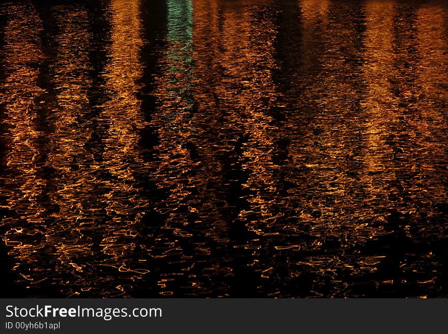 Orange lights reflecting on gently moving water. Orange lights reflecting on gently moving water