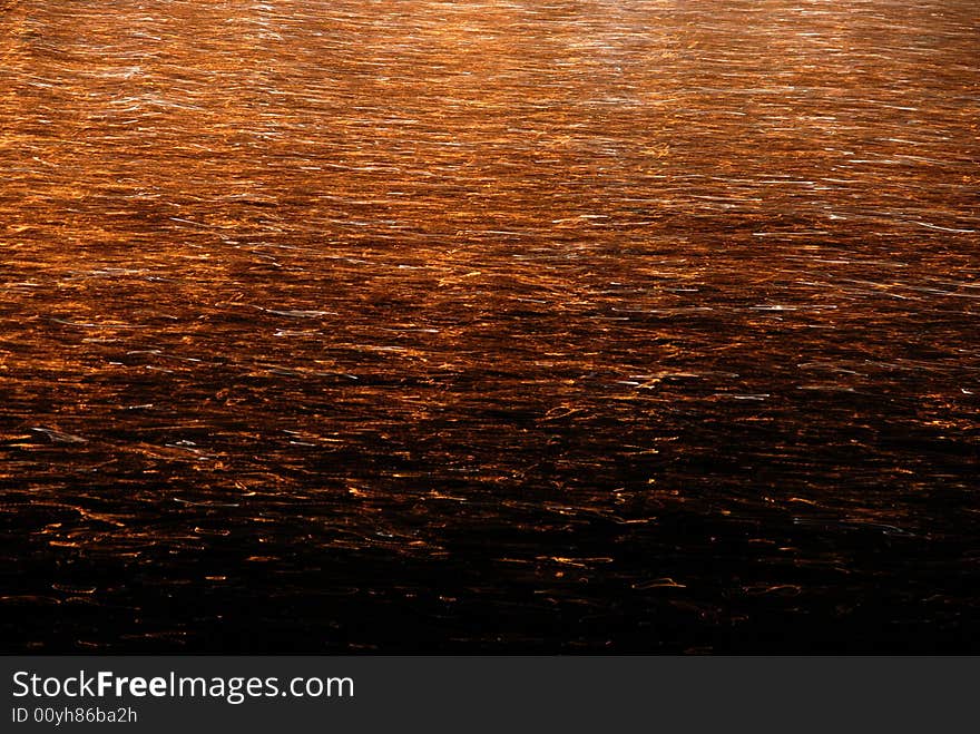 Orange lights reflecting on gently moving water. Orange lights reflecting on gently moving water