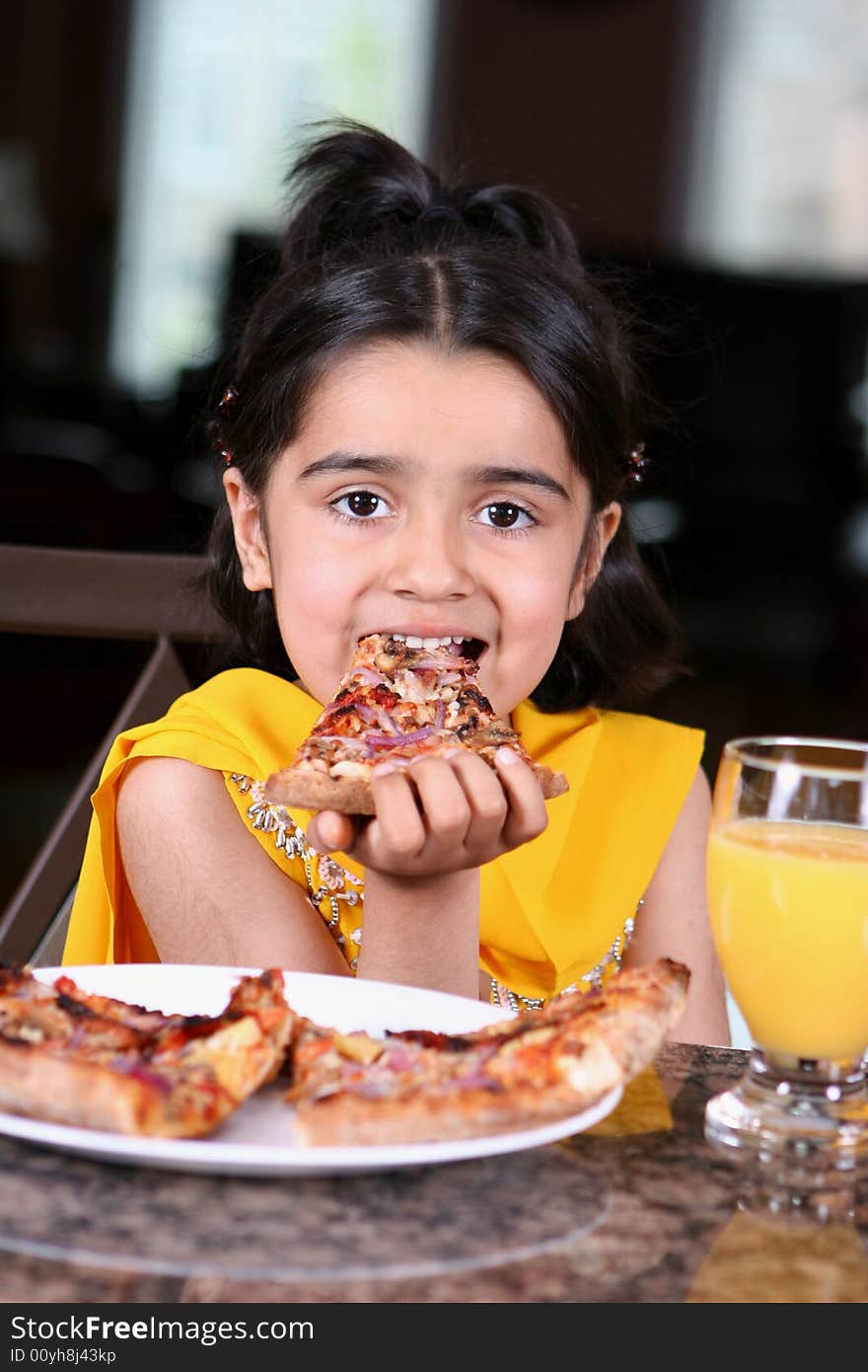 Little girl in east indian clothes holding a pizza slice. Little girl in east indian clothes holding a pizza slice