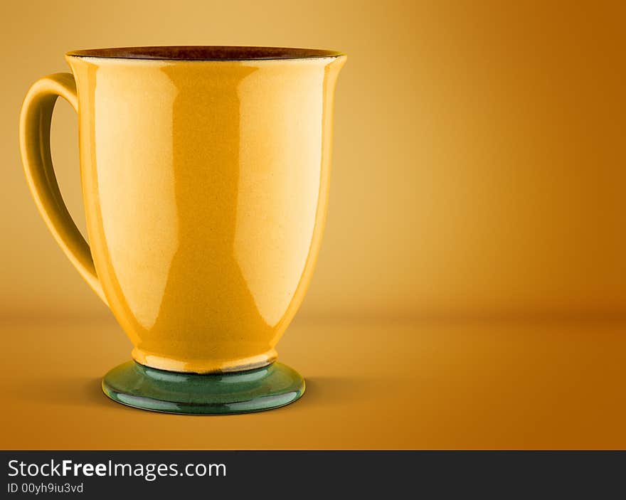 A yellow coffee or tea mug on a yellow background. A yellow coffee or tea mug on a yellow background.