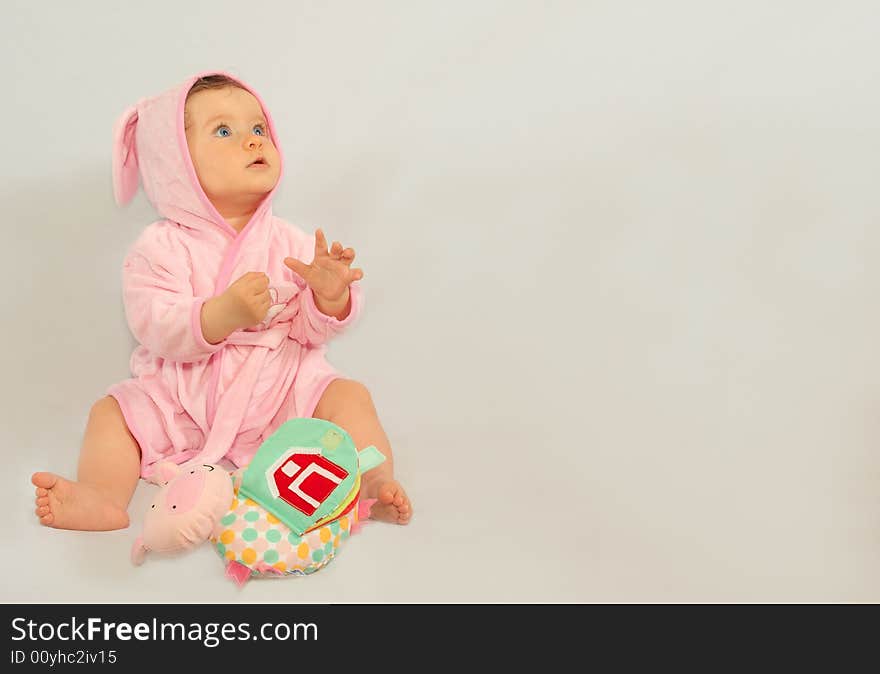 8 months old girl sitting after a bath wearing pink rabbit style bathrobe. 8 months old girl sitting after a bath wearing pink rabbit style bathrobe