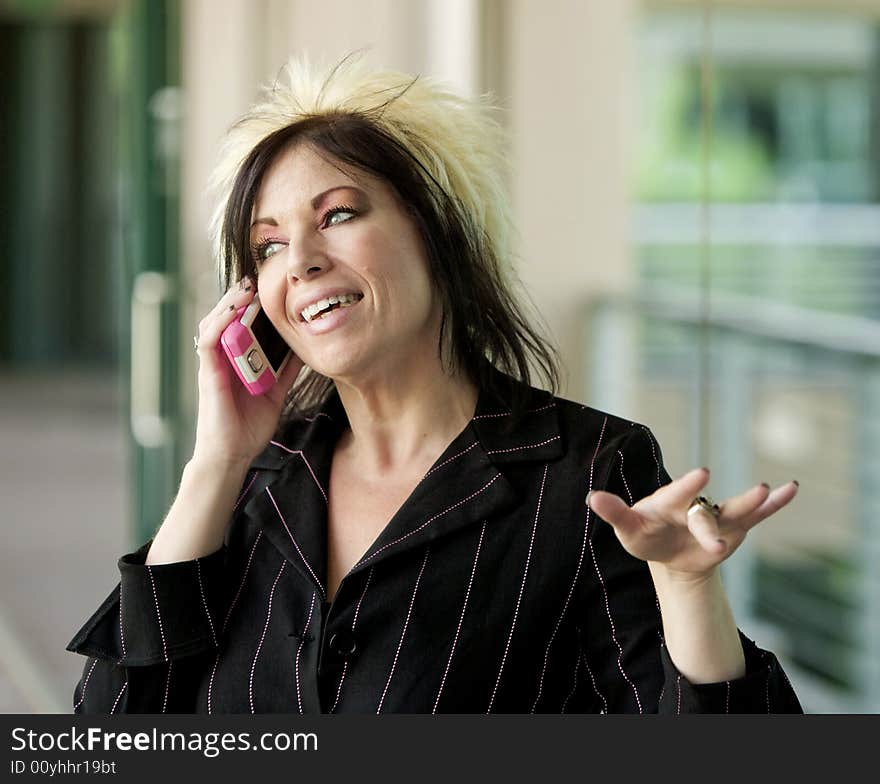 Modern businesswoman in an outdoor walkway talking on her cell phone. Modern businesswoman in an outdoor walkway talking on her cell phone