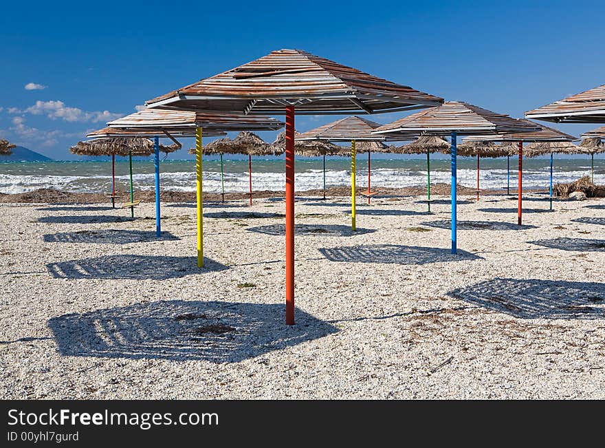 Set of beach umbrellas on sand making shadows under the blue clear sky in hot day. Set of beach umbrellas on sand making shadows under the blue clear sky in hot day