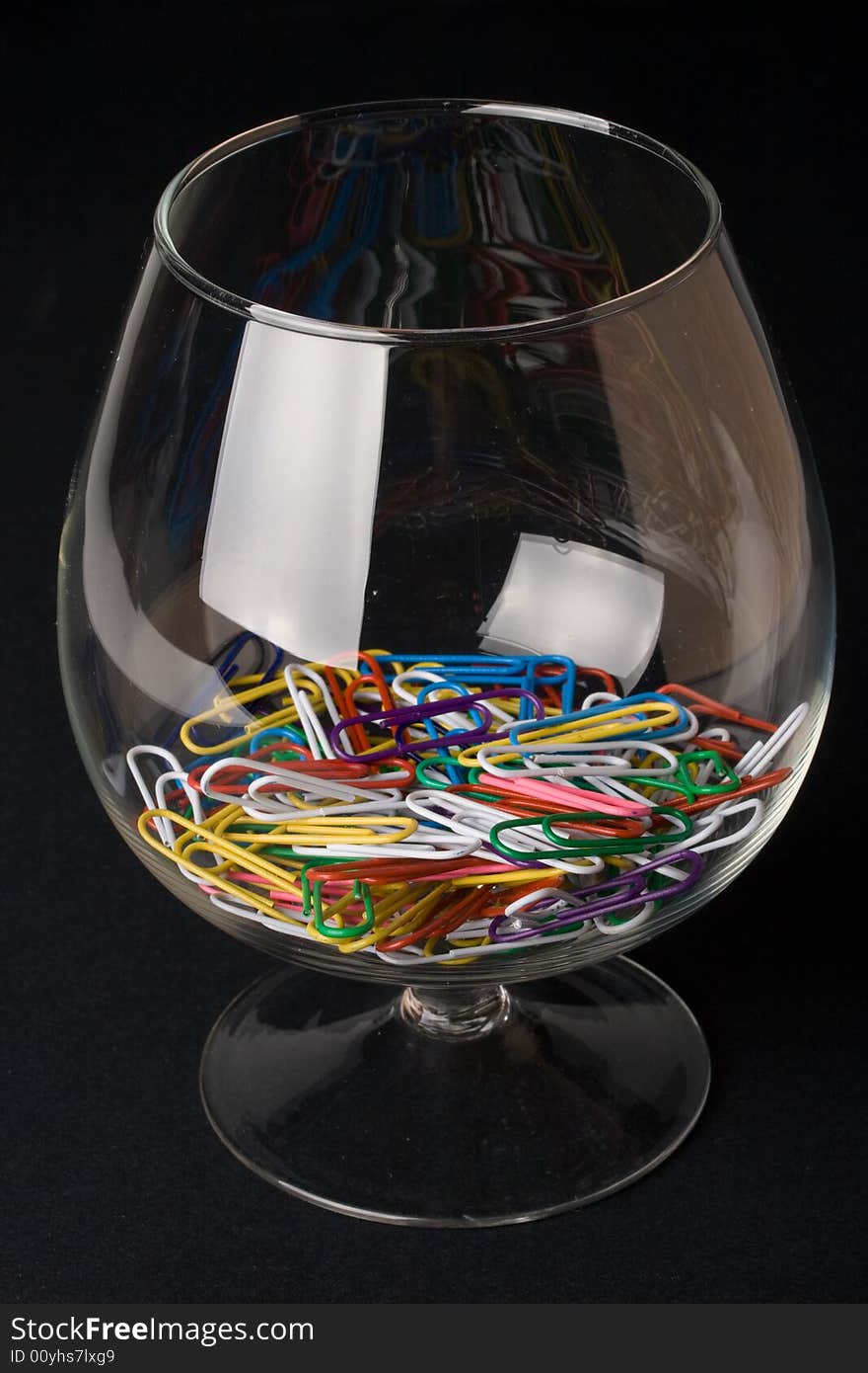 Colored paperclips in a glass on a black background. Close up. Selective focus.