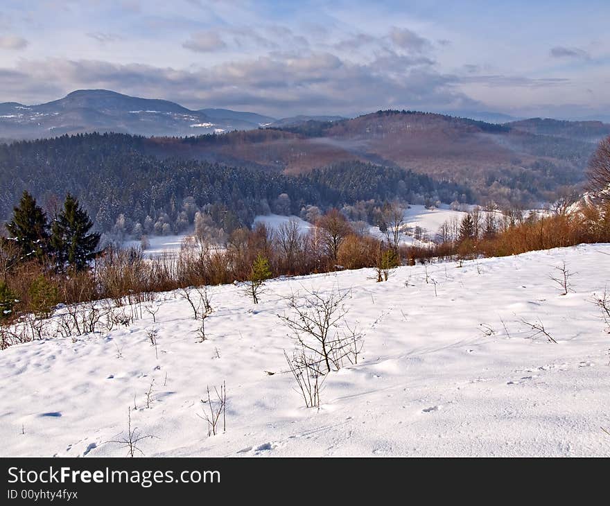 Winter landscape with snow covered ground and distant mountains