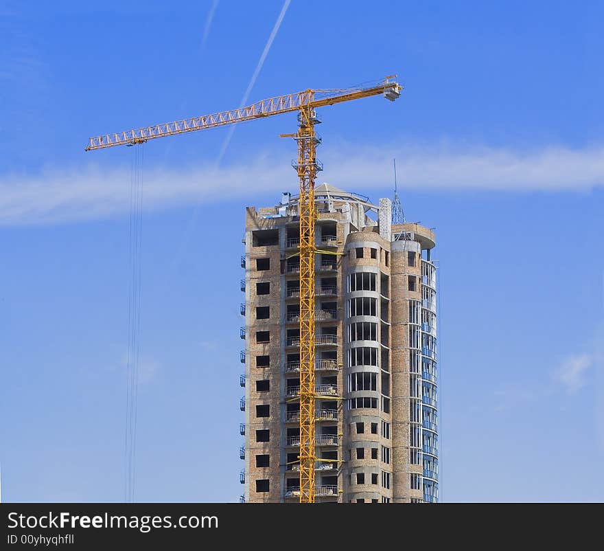 High rise construction site with crane against a bright blue sky. High rise construction site with crane against a bright blue sky.