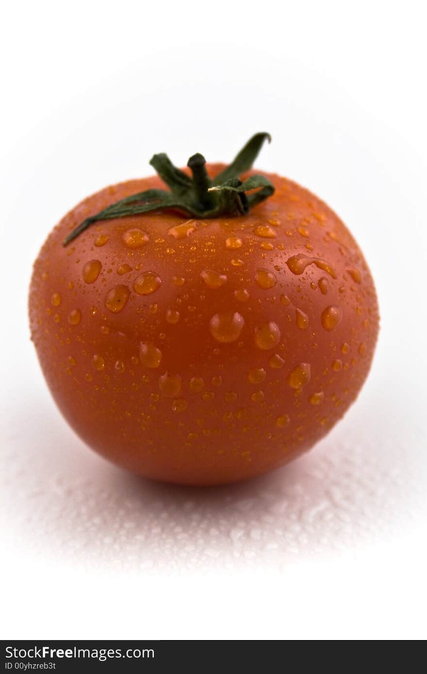 One red tomato with drops on it, close-up