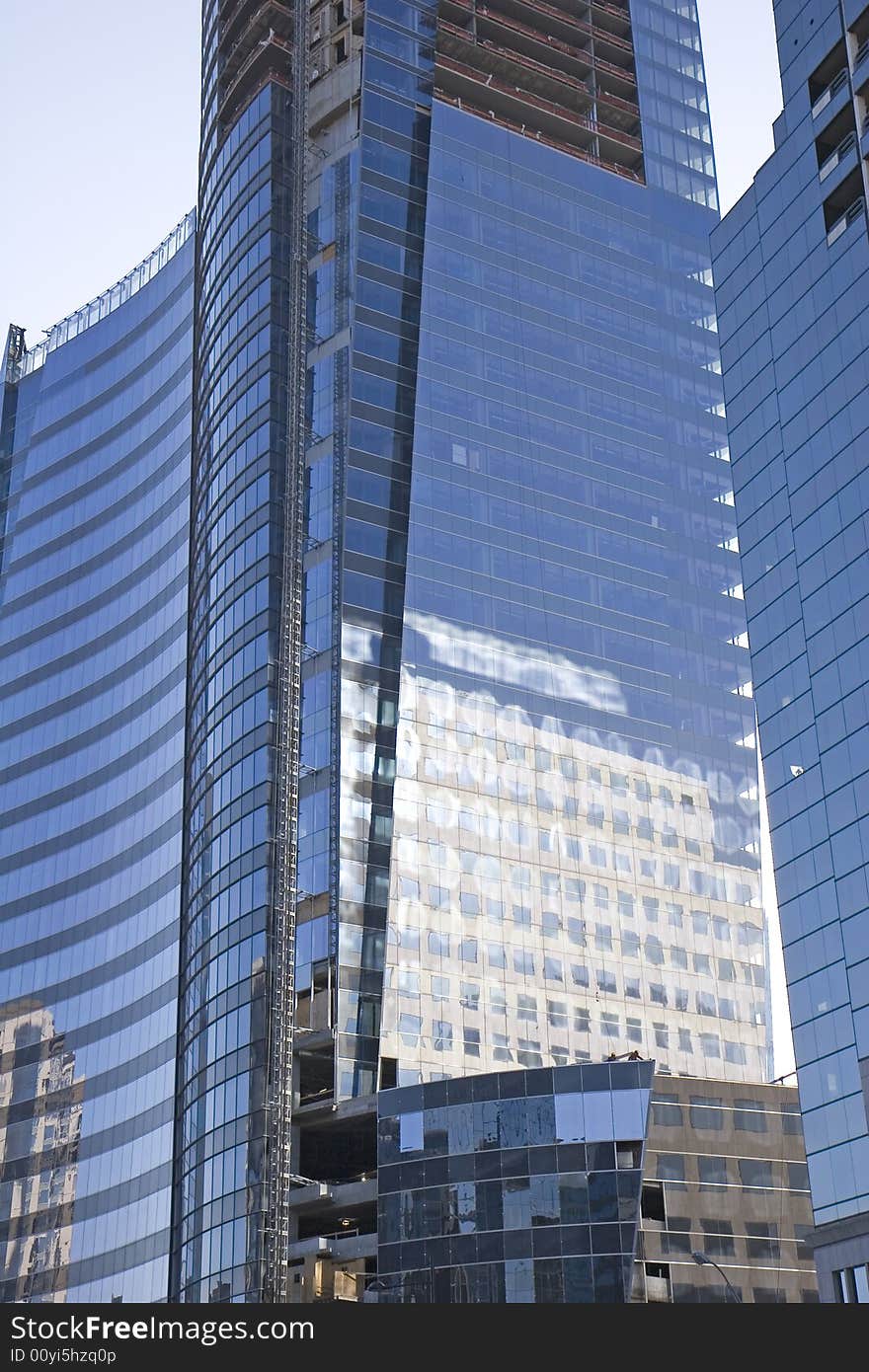 A new curving blue glass office tower under construction with building reflected. A new curving blue glass office tower under construction with building reflected