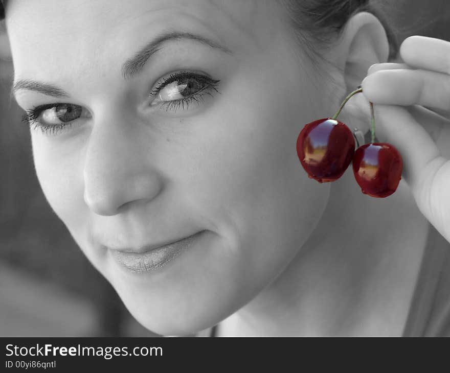 Young girl in black and white with colourful cherry in her fingers. Young girl in black and white with colourful cherry in her fingers