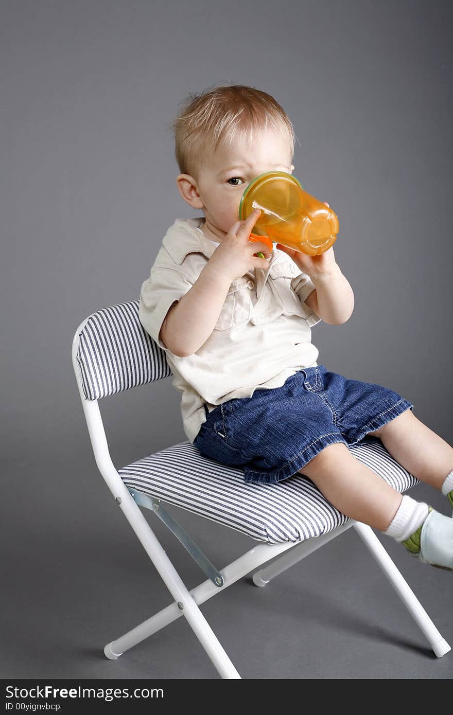 Little blond boy drinking out of his juice cup. Little blond boy drinking out of his juice cup.