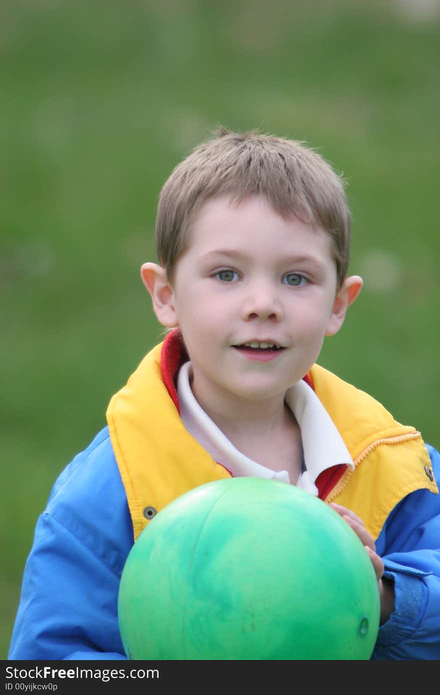 Young boy holding a green ball, looks as if he's getting ready to toss it. Young boy holding a green ball, looks as if he's getting ready to toss it.