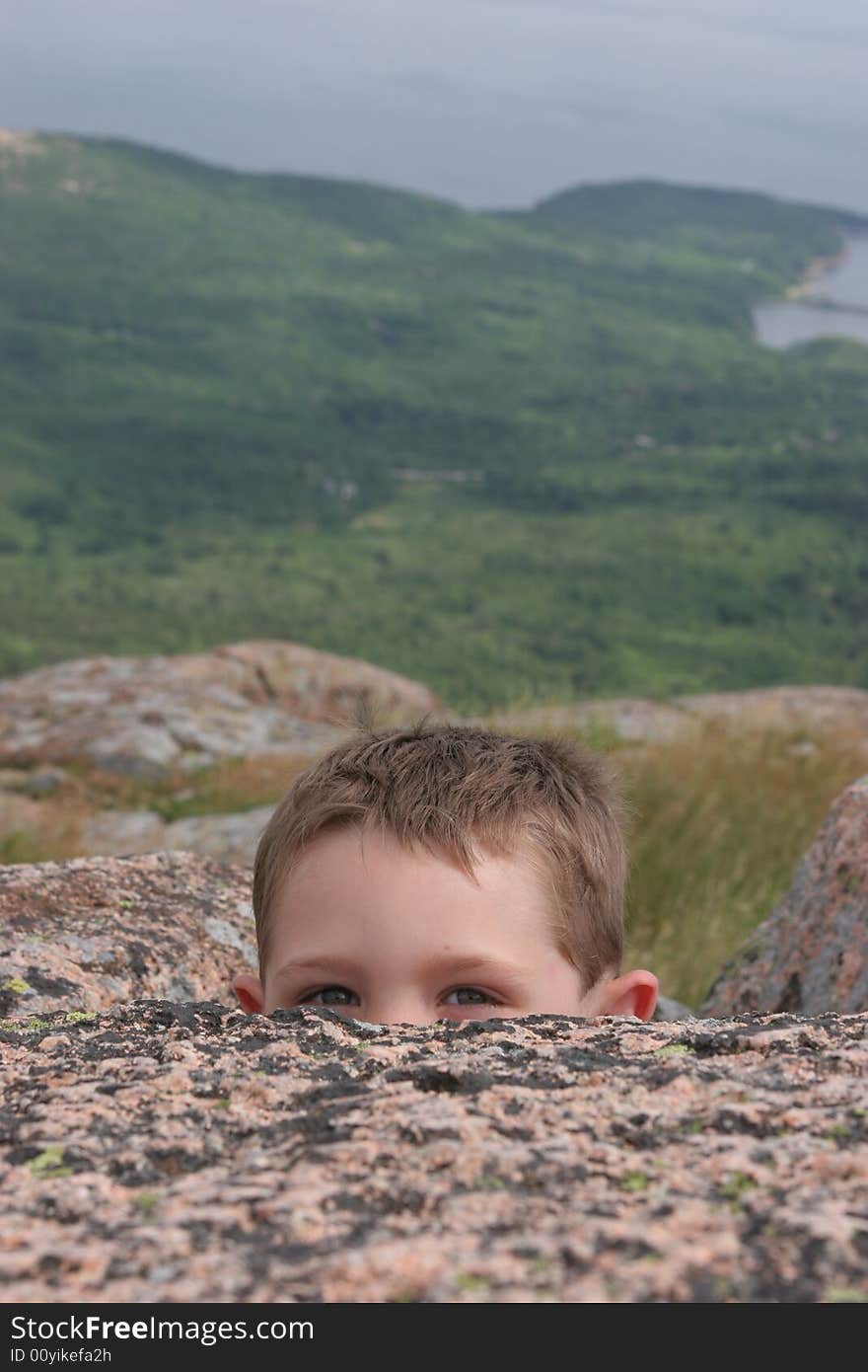 Child peeking over a rock