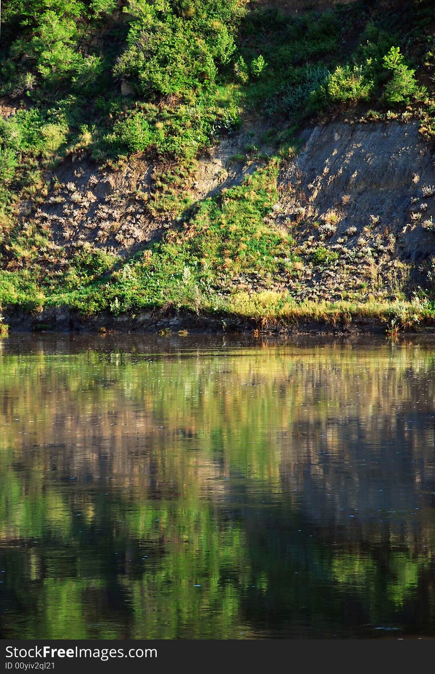 A beautifully-green landscape reflected in a running river. A beautifully-green landscape reflected in a running river.