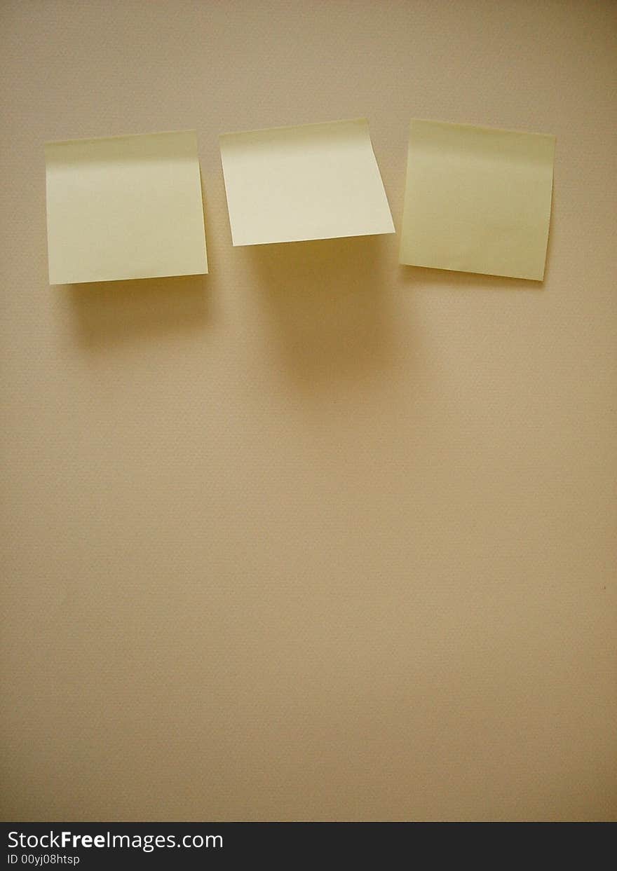 Three yellow sticky notes an the wall, without notes.