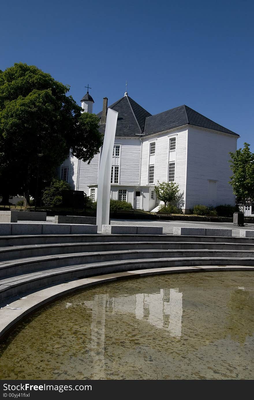 Church in Norway with statue, stairs and water.