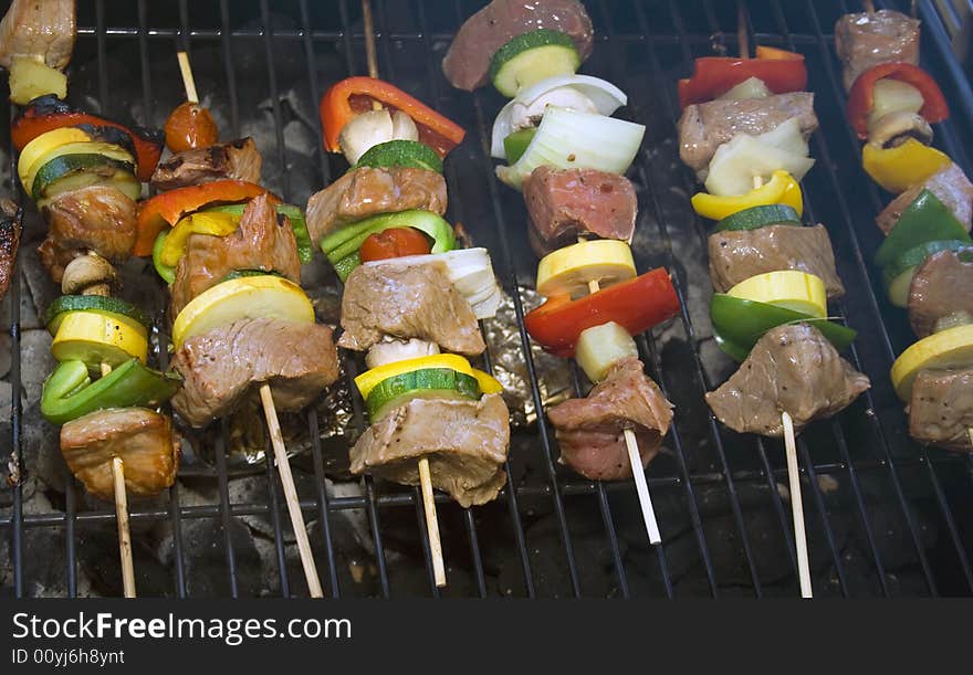 Several Shishkabobs on a grill