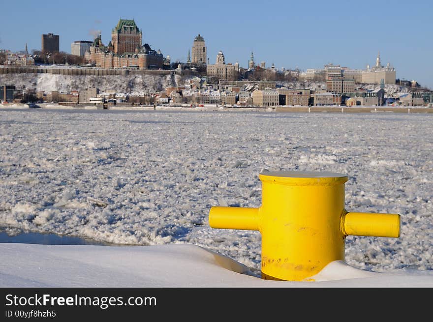 This yellow bollard seems very useless half buried in the snow. Facing the frozen Saint-Lawrence River, it waits quietly the spring to see ships coming to moor again. In the background we can see Quebec City. This yellow bollard seems very useless half buried in the snow. Facing the frozen Saint-Lawrence River, it waits quietly the spring to see ships coming to moor again. In the background we can see Quebec City.