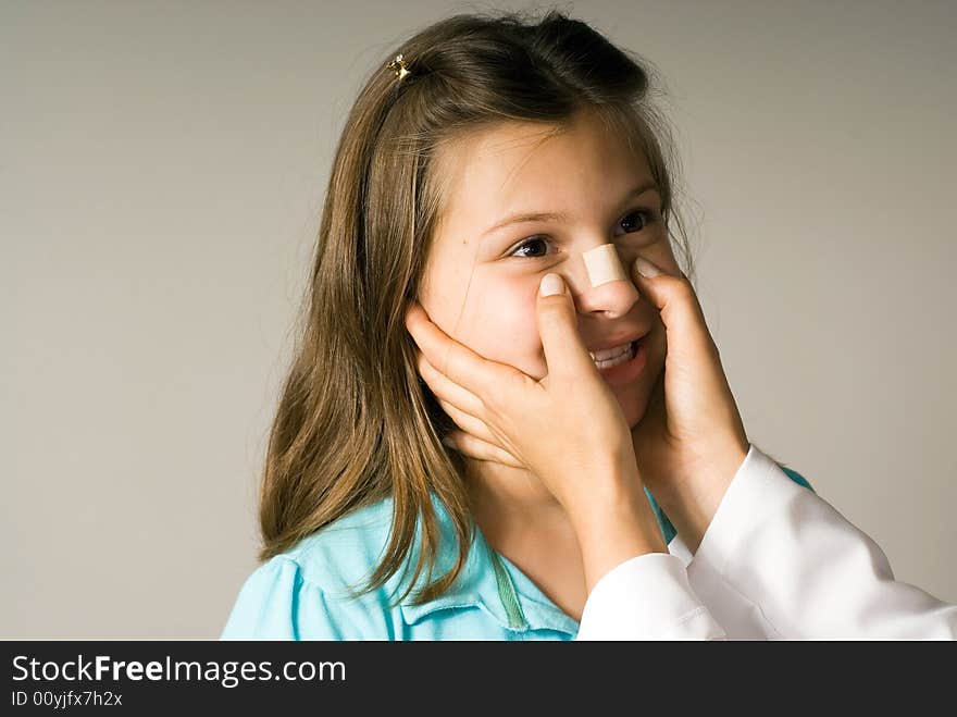 Young girl smiles while a band-aid is applied to her nose. She is happy to be taken care of. Horizontally framed photograph. Young girl smiles while a band-aid is applied to her nose. She is happy to be taken care of. Horizontally framed photograph