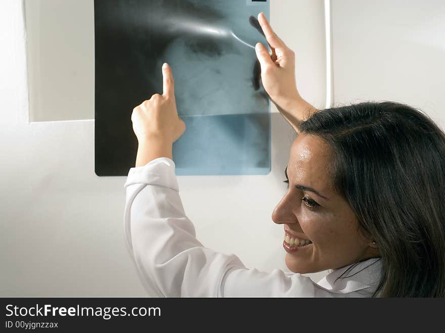 Female Doctor points at an x-ray while she smiles. Horizontally framed photograph. Female Doctor points at an x-ray while she smiles. Horizontally framed photograph.