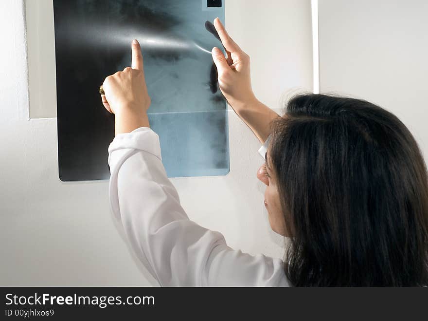 Female Doctor points to an x-ray. Horizontally framed photograph. Female Doctor points to an x-ray. Horizontally framed photograph