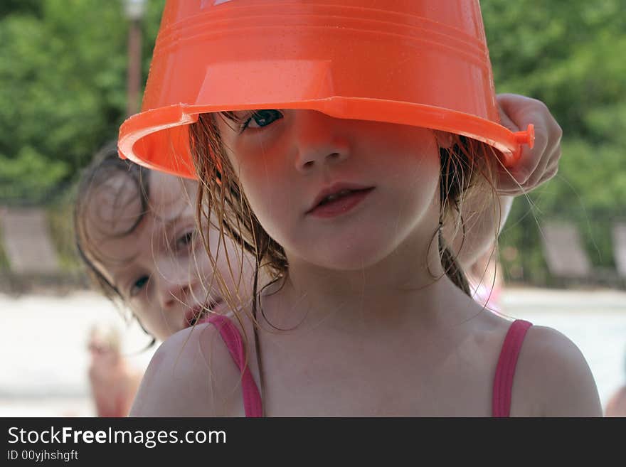 A little girl at the pool with a bucket over her head. A little girl at the pool with a bucket over her head