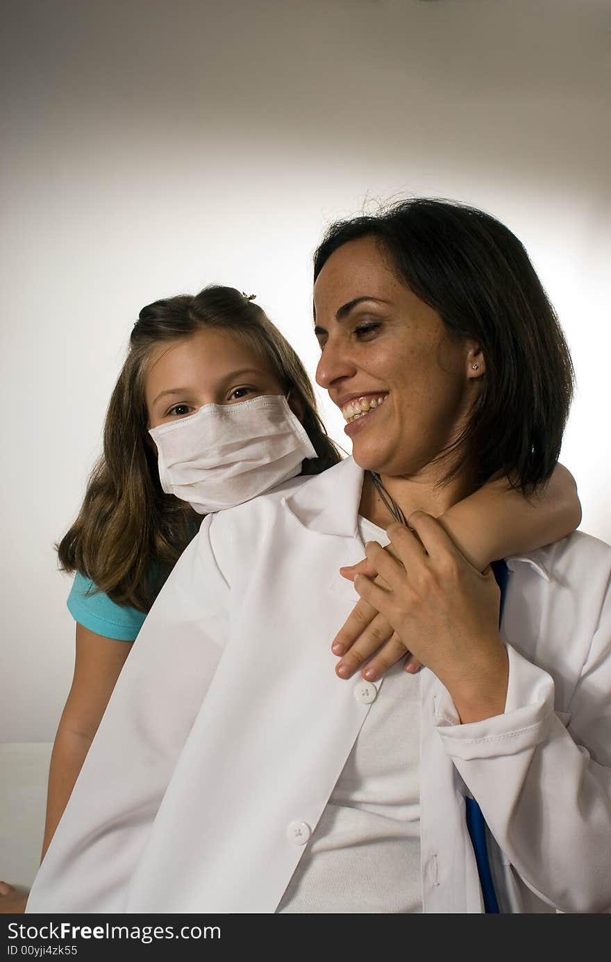 Young girl wearing a mask puts her arm lovingly around the doctor who looks at her playfully. They are playing around and being silly and enjoying each others company. Vertically framed photograph. Young girl wearing a mask puts her arm lovingly around the doctor who looks at her playfully. They are playing around and being silly and enjoying each others company. Vertically framed photograph