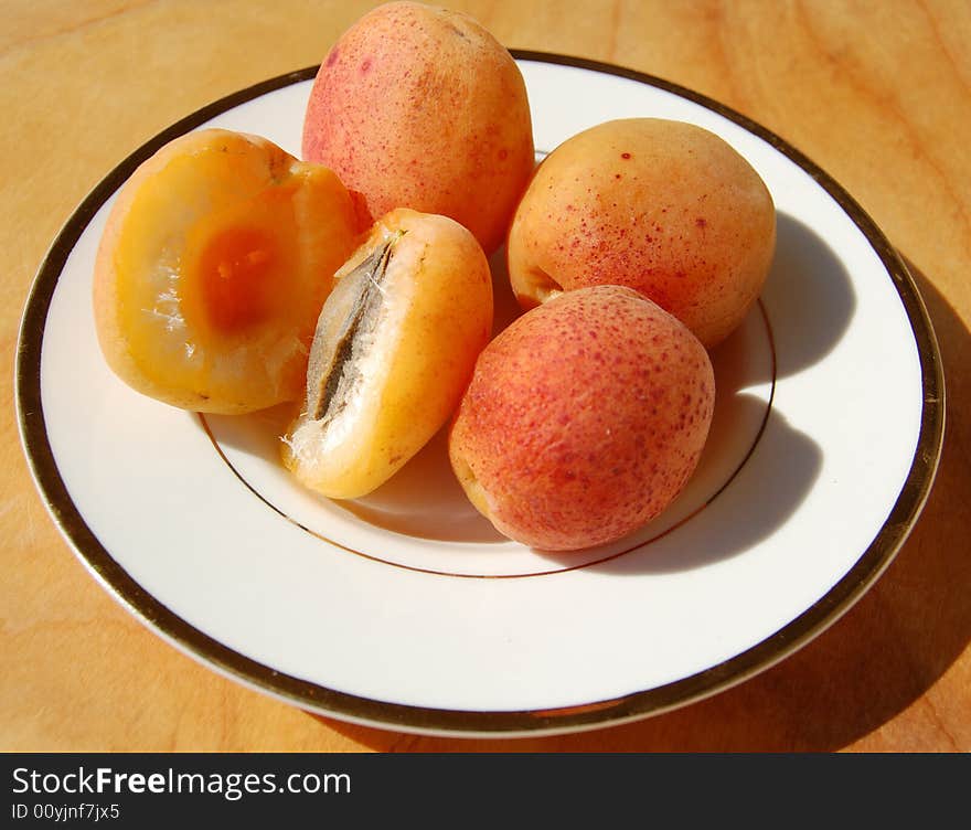 Apricots on the white dish with golden border