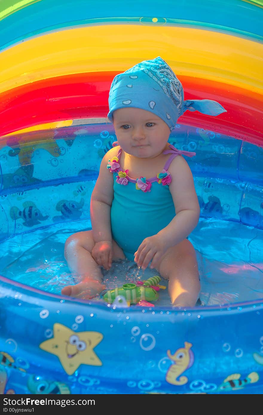 8 month old girl sitting in a small swimming pool. 8 month old girl sitting in a small swimming pool